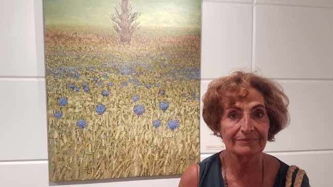 Teresa de Paz artista posando junto a uno de sus cuadros